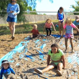 Children playing in outdoor mud slide