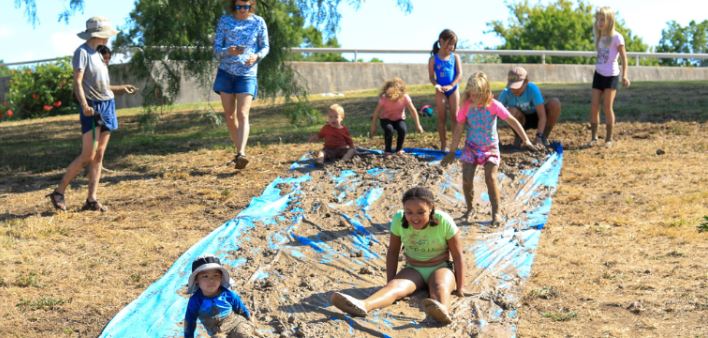 Children playing in outdoor mud slide