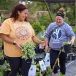 Two shoppers holding potted plants at the San Antonio Botanical Gardens