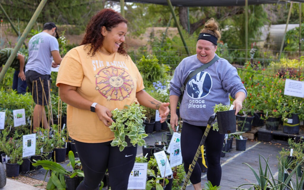 Two shoppers holding potted plants at the San Antonio Botanical Gardens