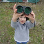 Young bird watcher holding up binoculars