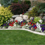 A colorful mixed border of flowers adjacent to a green turf lawn